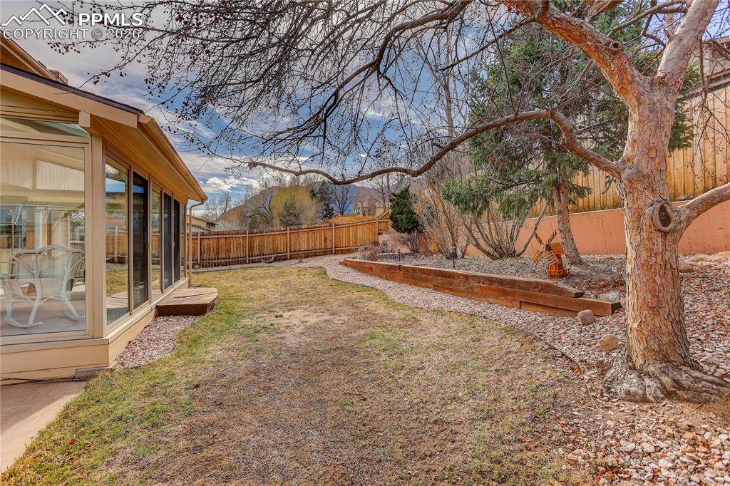Image 28 of 37: Backyard with views of Cheyenne Mtn. The Cherry tree in the foreground will