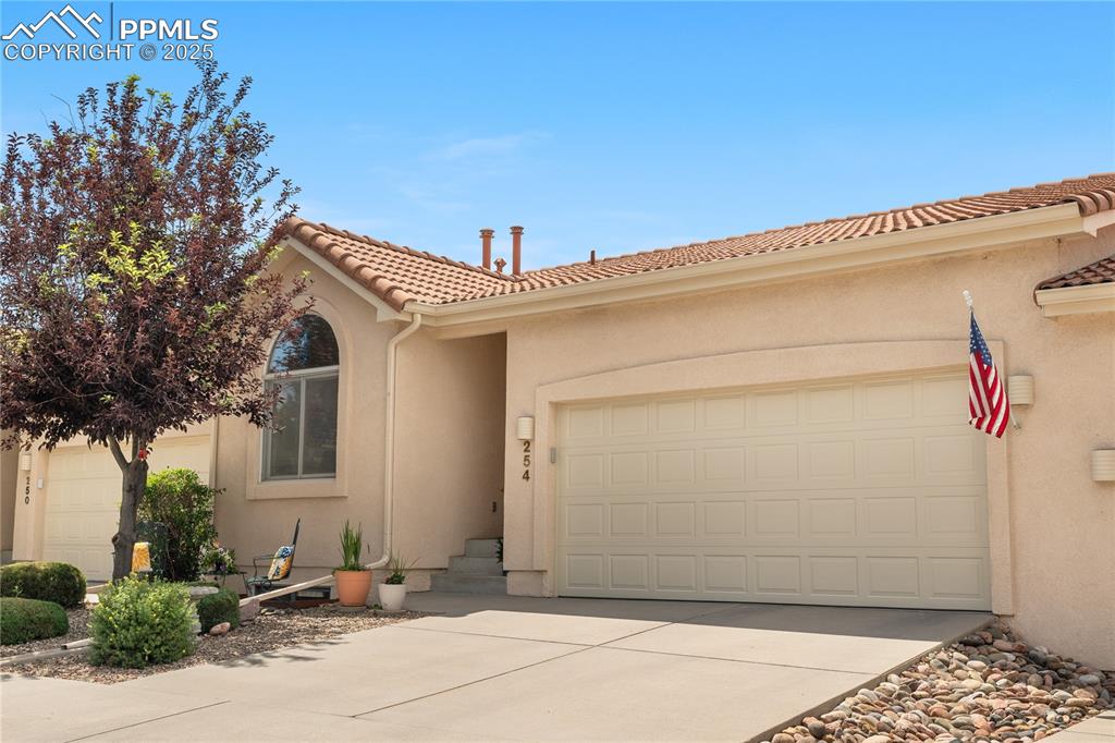 Caption: Mediterranean / spanish house with a garage, driveway, stucco siding, and a tiled roof