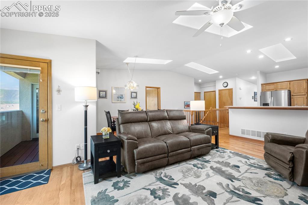 Image 18 of 49: Living room featuring a skylight, light wood-type flooring, lofted ceiling,