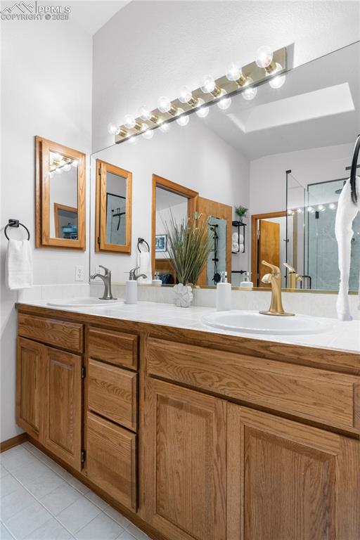 Image 28 of 49: Bathroom featuring double vanity, tile patterned flooring, and a shower sta