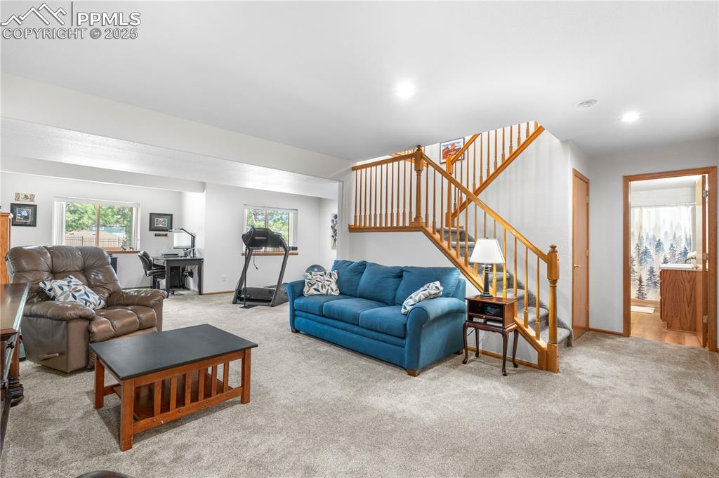 Image 31 of 49: Carpeted living area featuring stairway and recessed lighting