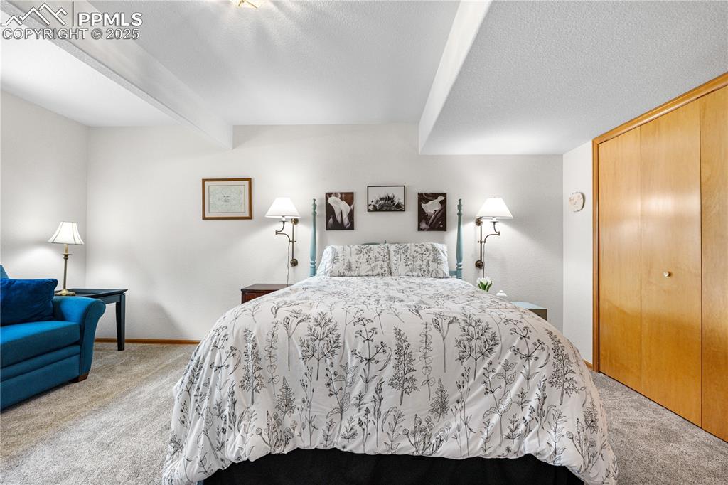 Image 35 of 49: Bedroom with carpet floors, beam ceiling, a closet, and a textured ceiling