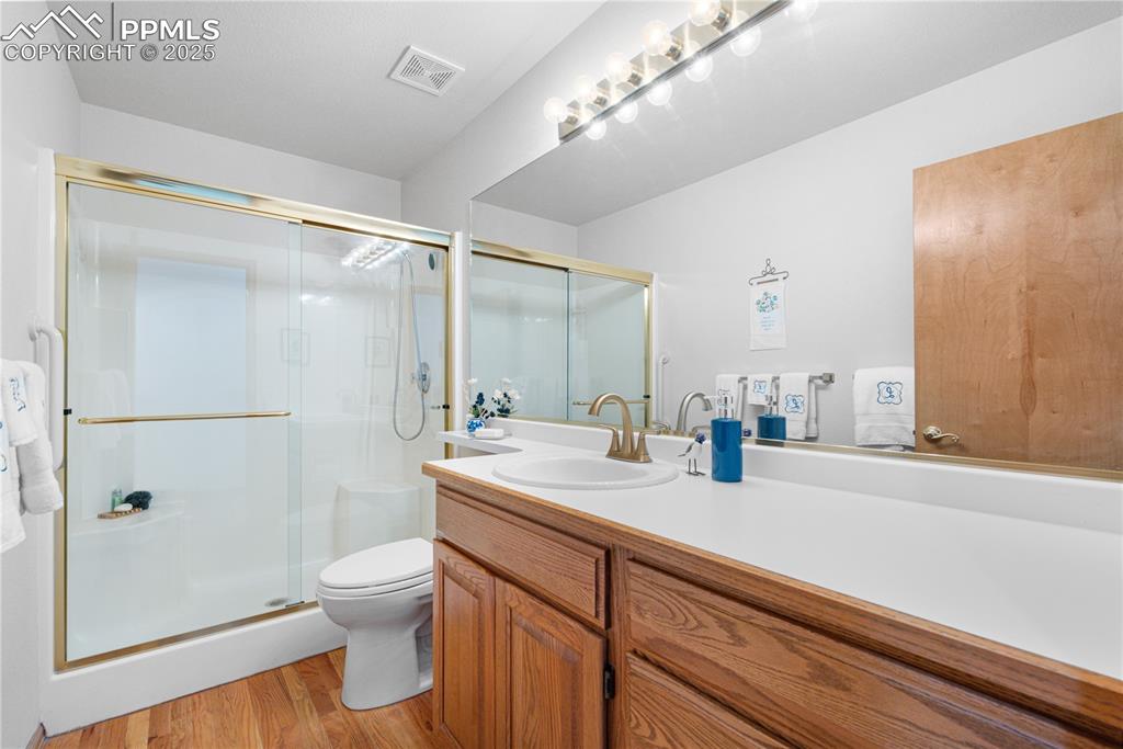 Image 4 of 49: Full bath with vanity, wood finished floors, and a shower stall