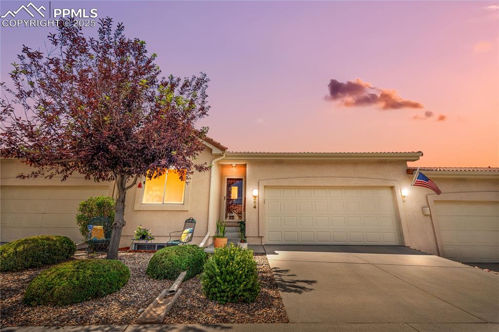 Image 42 of 49: View of front facade with stucco siding, driveway, an attached garage, and