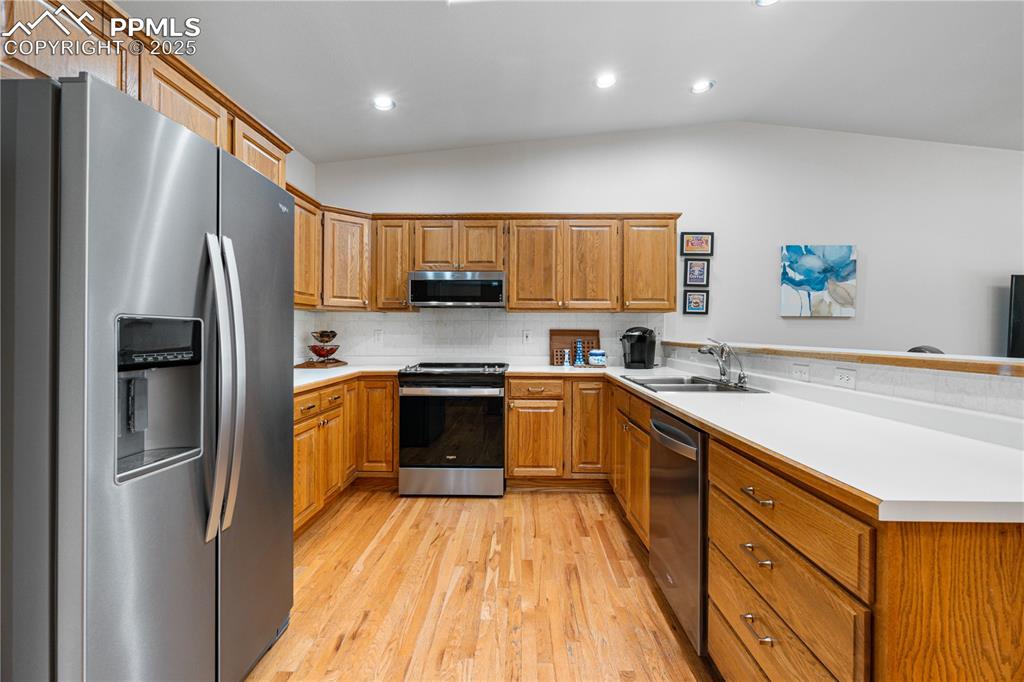 Image 6 of 49: Kitchen with stainless steel appliances, a peninsula, light wood finished f