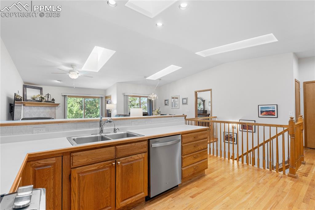 Image 8 of 49: Kitchen featuring stainless steel dishwasher, a skylight, light wood-style