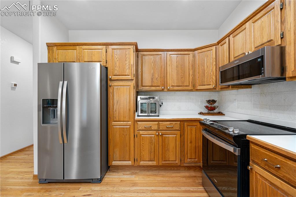 Image 9 of 49: Kitchen featuring stainless steel appliances, light countertops, backsplash