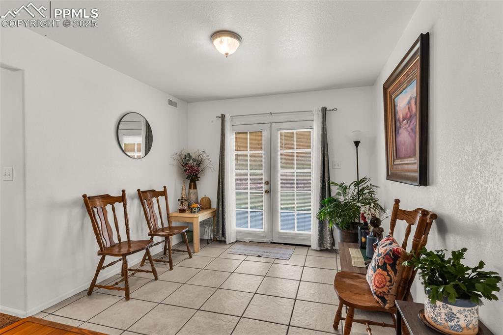 Image 13 of 20: Living area with french doors and light tile patterned flooring