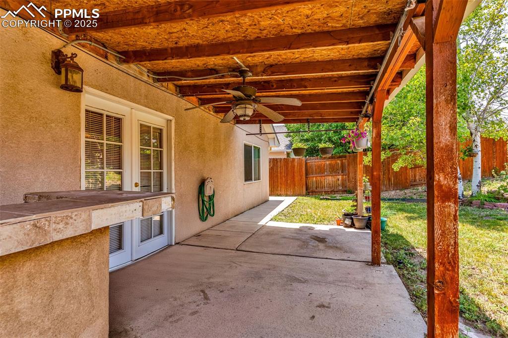 Image 15 of 20: Fenced backyard with a patio, ceiling fan, and exterior kitchen