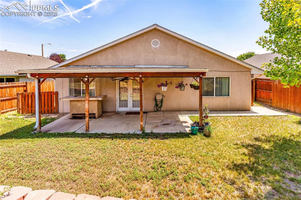 Image 18 of 20: Back of property with french doors, a fenced backyard, stucco siding, a pat