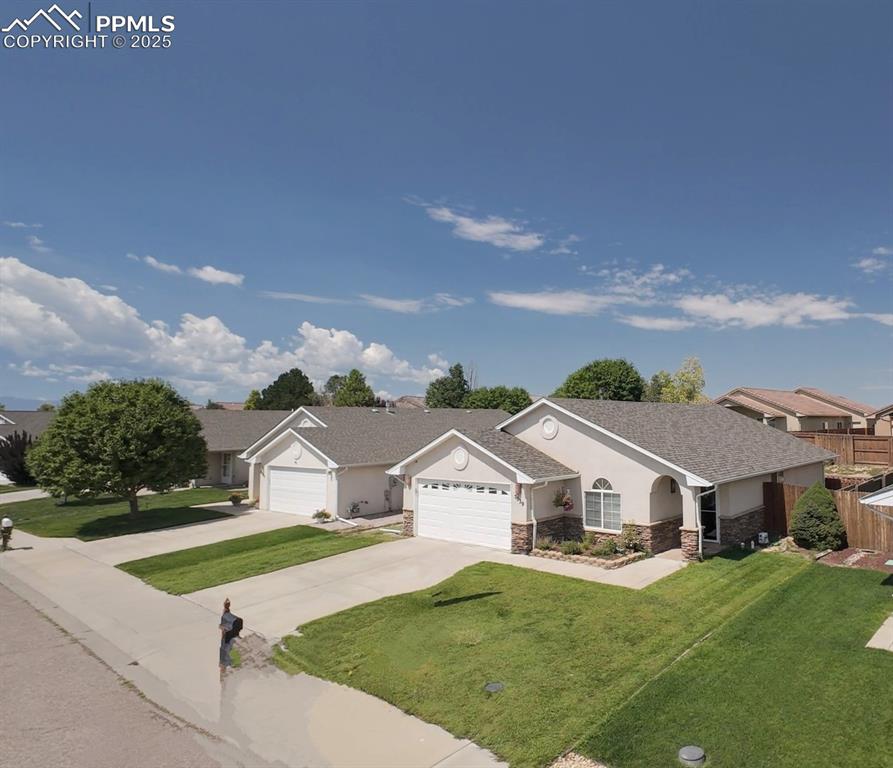 Image 20 of 20: Ranch-style house with stone siding, stucco siding, a front lawn, and concr