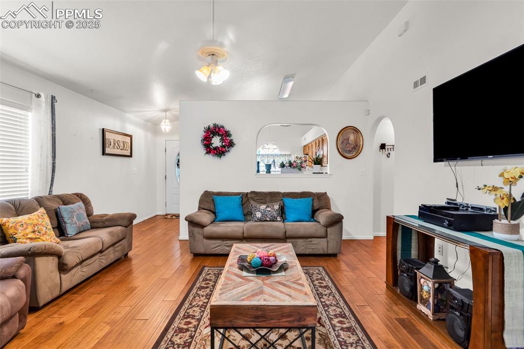 Image 6 of 20: Living room featuring arched walkways and light wood-type flooring