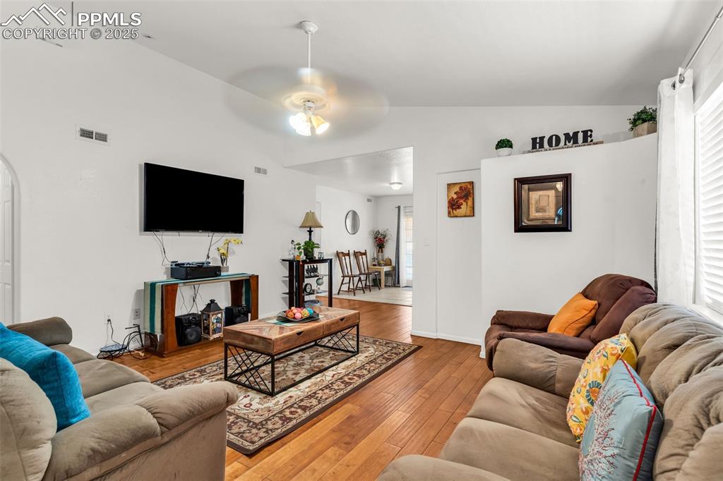 Image 7 of 20: Living room with vaulted ceiling, a ceiling fan, hardwood / wood-style floo