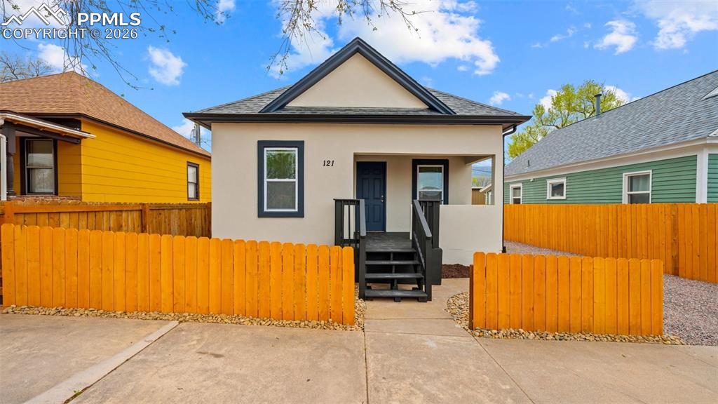 Image 1 of 36: View of front facade with stucco siding, a fenced front yard, roof with shi
