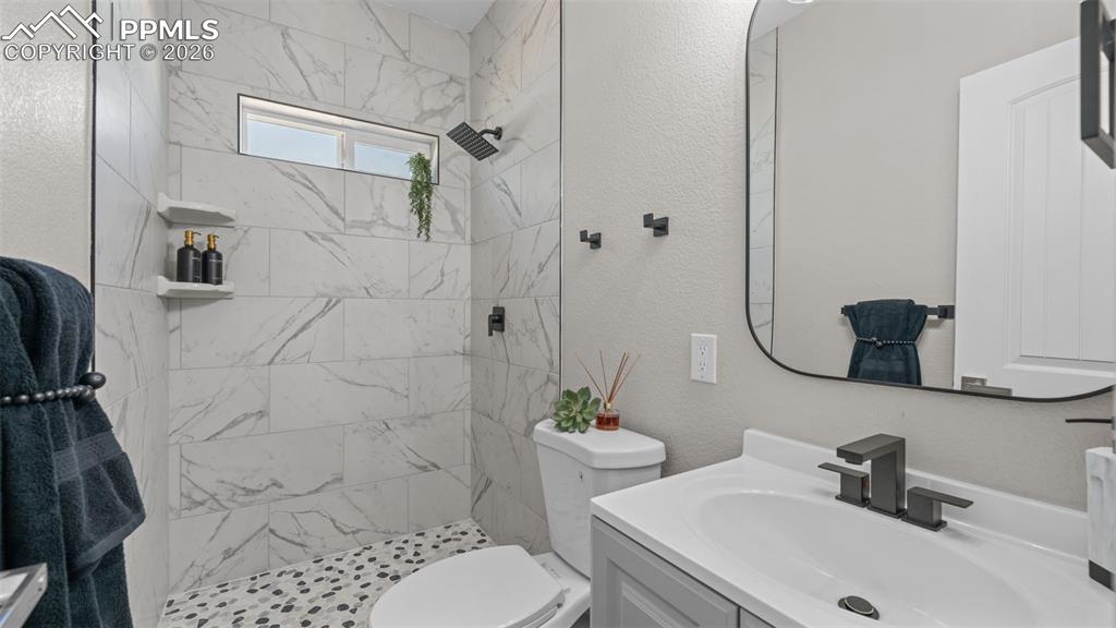 Image 18 of 36: Bathroom with vanity, a tile shower, and a textured wall
