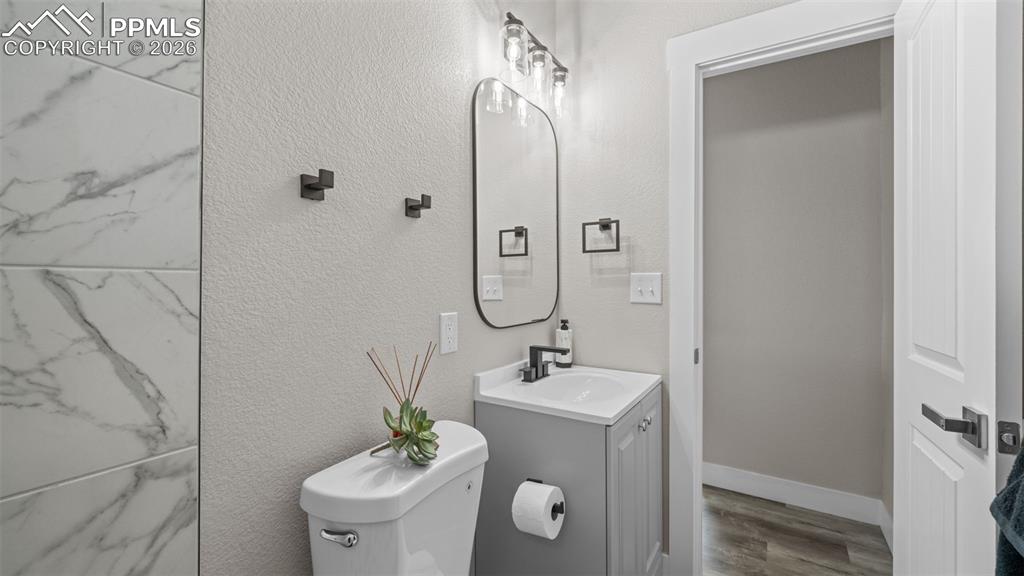 Image 19 of 36: Half bathroom featuring vanity, a textured wall, and wood finished floors