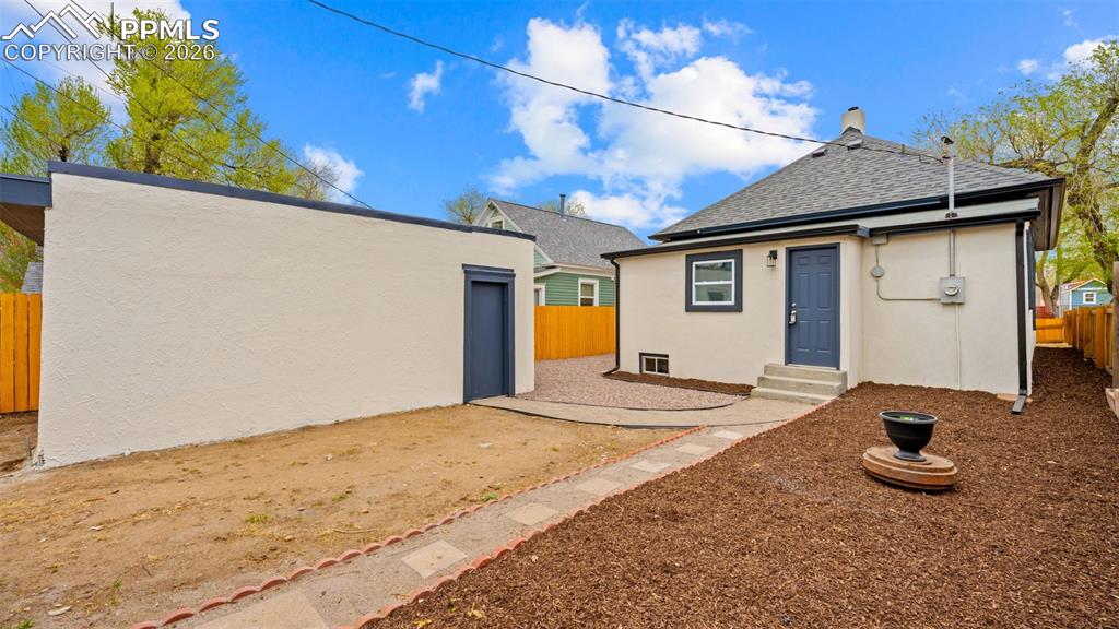 Image 25 of 36: Back of property with stucco siding, roof with shingles, and a chimney