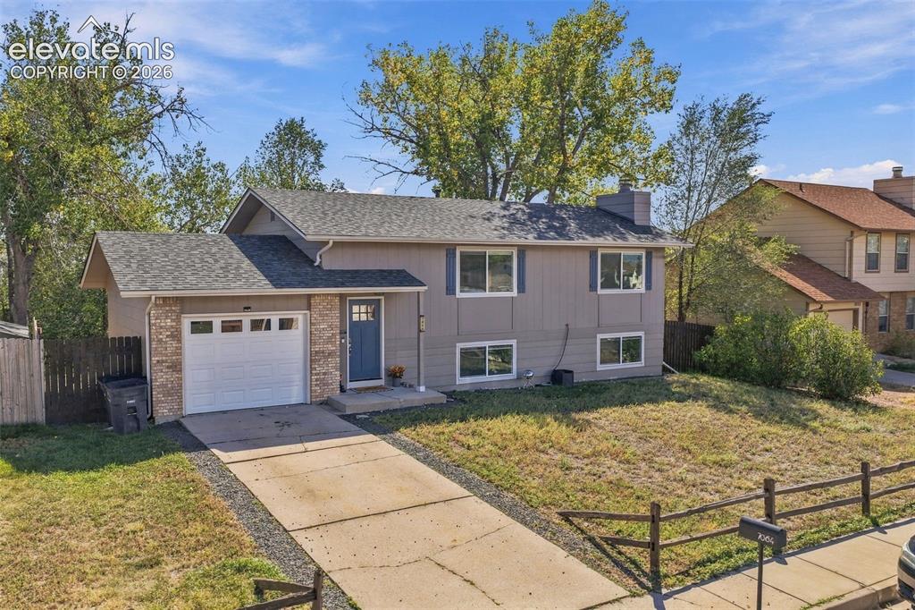 Caption: Split-level residence featuring a partial brick facade and an attached garage