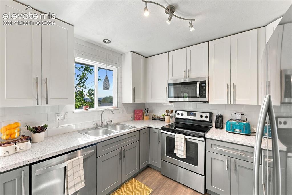 Image 10 of 46: Modern kitchen featuring two-tone cabinetry, stainless steel appliances, a