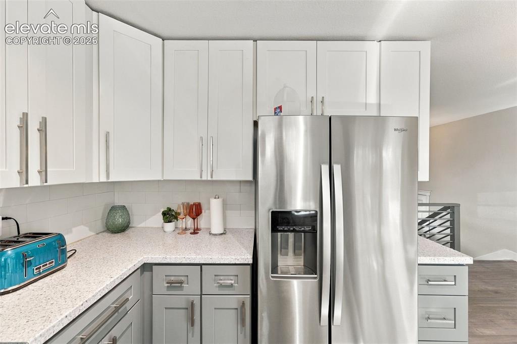 Image 12 of 46: Stainless steel side-by-side refrigerator, white upper cabinetry, grey lowe