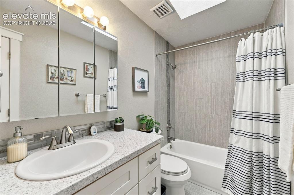 Image 13 of 46: Built-in vanity with a speckled countertop, undermount sink, and brushed ni