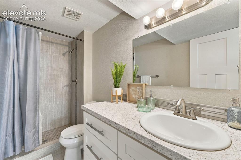 Image 22 of 46: White vanity with brushed nickel hardware, speckled countertop, and an oval