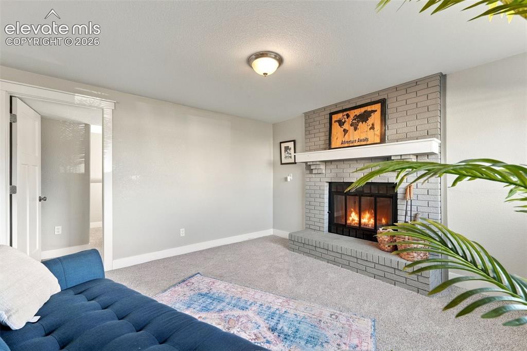 Image 26 of 46: Brick fireplace with a substantial hearth, mantel, and metal firebox
