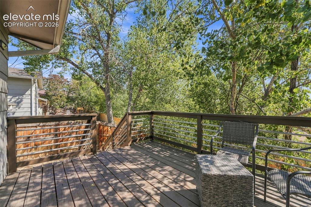 Image 35 of 46: Expansive wood deck with a dark wood railing and horizontal metal balusters