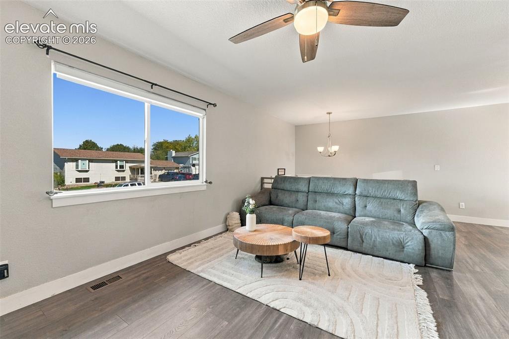 Image 6 of 46: Large window with white trim, ceiling fan with integrated lighting, wood-fi