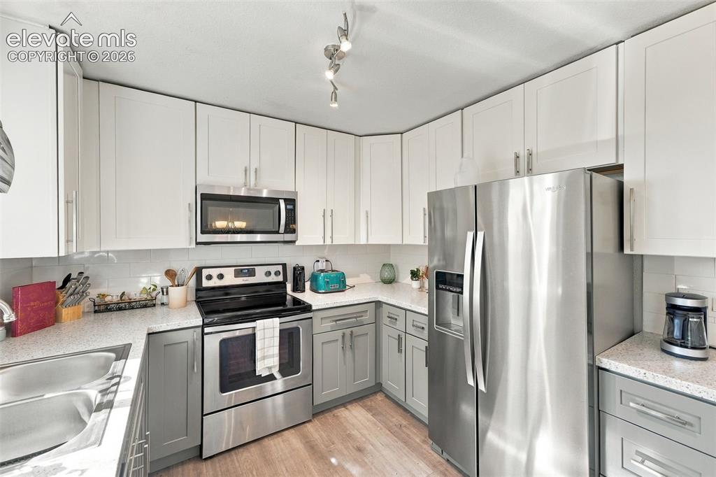 Image 9 of 46: Kitchen with two-tone cabinetry, stainless steel appliances, speckled count