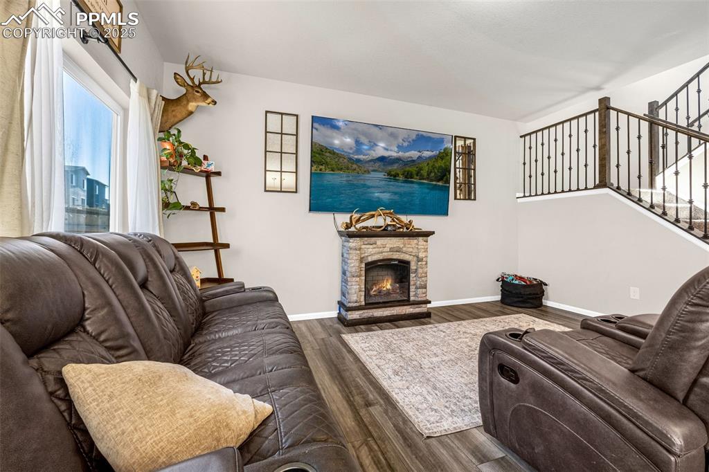 Image 12 of 35: Living area featuring wood finished floors, stairway, and a fireplace