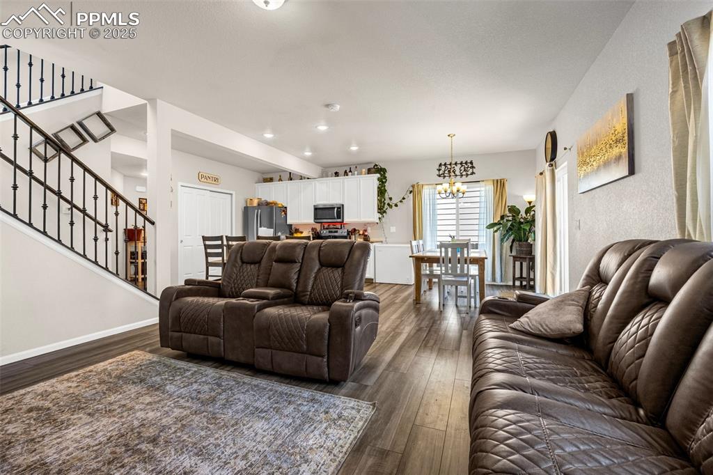 Image 16 of 35: Living area featuring a chandelier, dark wood-style floors, stairway, and r
