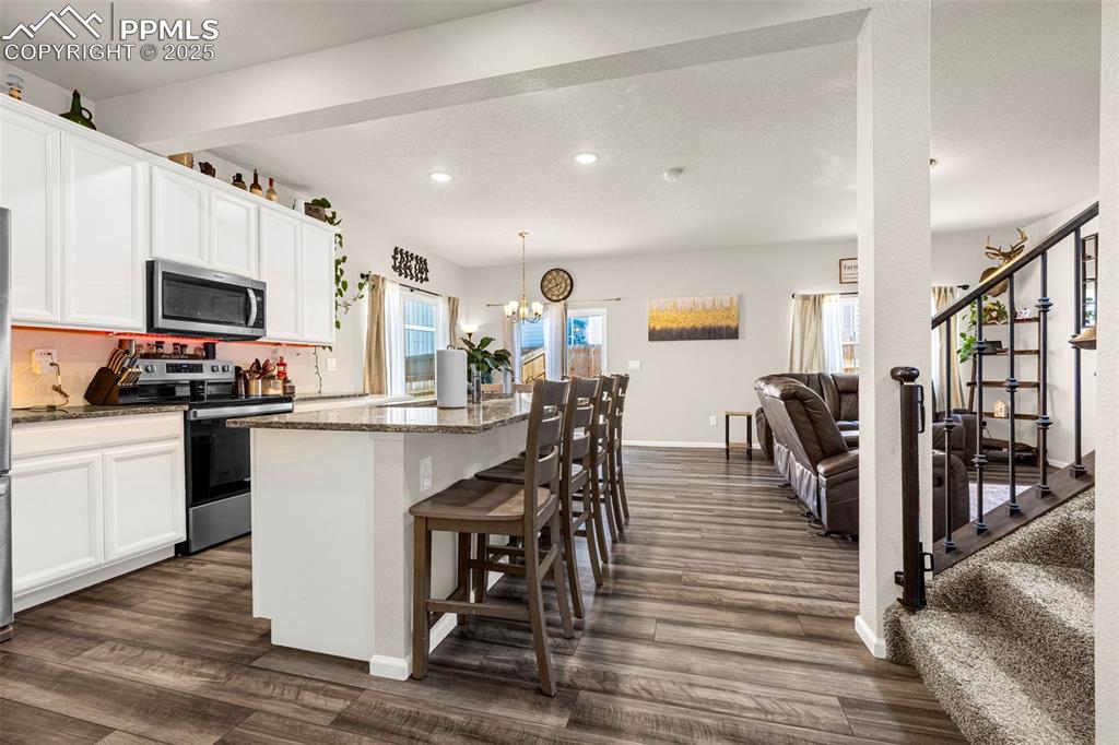 Image 17 of 35: Kitchen with appliances with stainless steel finishes, white cabinets, dark