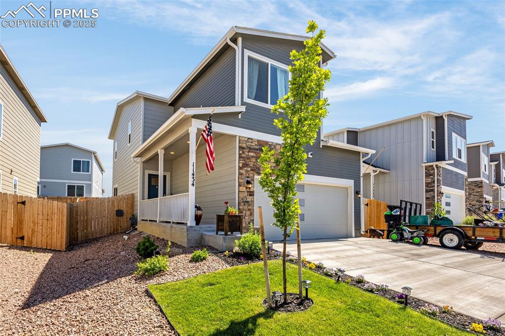 Image 2 of 35: View of front of home featuring covered porch, stone siding, and driveway