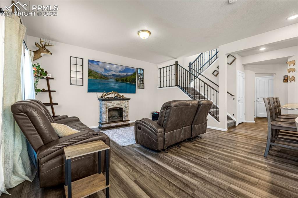Image 21 of 35: Living area featuring dark wood-style floors, stairway, a stone fireplace, 