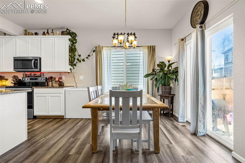 Image 22 of 35: Dining area with a chandelier, wood finished floors, and plenty of natural 