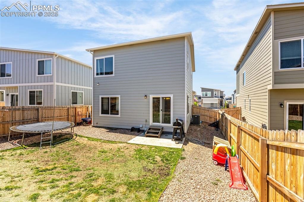 Image 27 of 35: Back of house featuring a trampoline, a fenced backyard, entry steps, and a