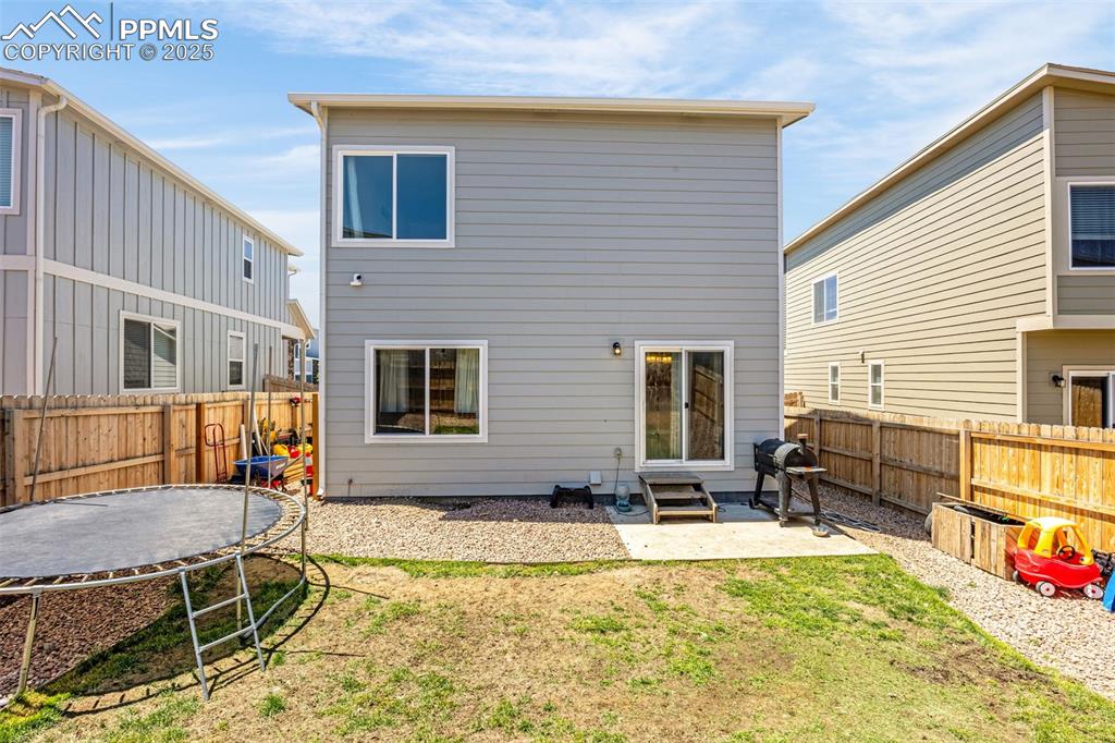 Image 28 of 35: Back of property with a trampoline, entry steps, a fenced backyard, and a p