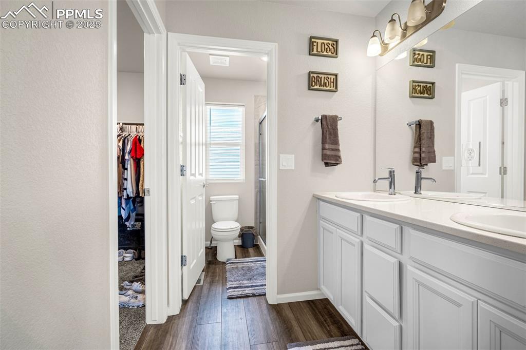 Image 9 of 35: Bathroom with wood finished floors, a shower stall, double vanity, and a wa