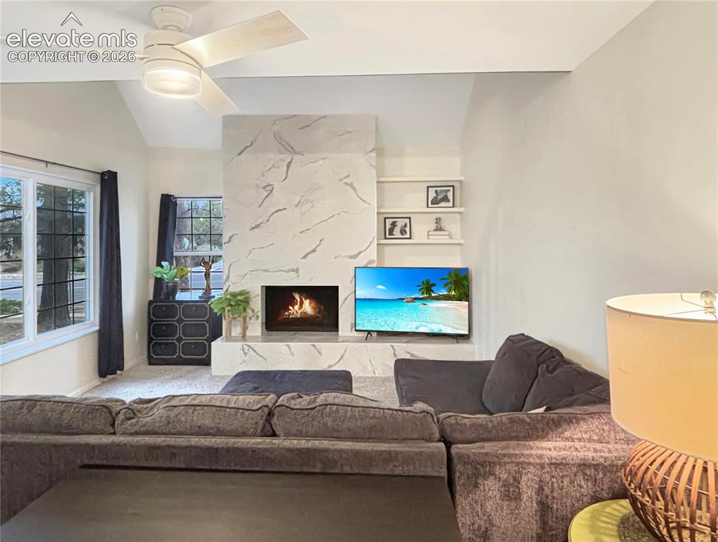 Image 13 of 44: Living area featuring a floor-to-ceiling fireplace with a stone-finish faca