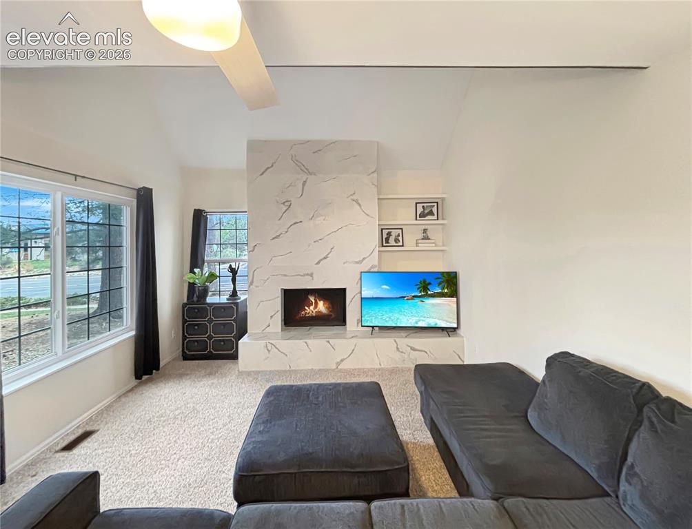 Image 29 of 44: Vaulted ceiling living room featuring a modern fireplace with a marble-look