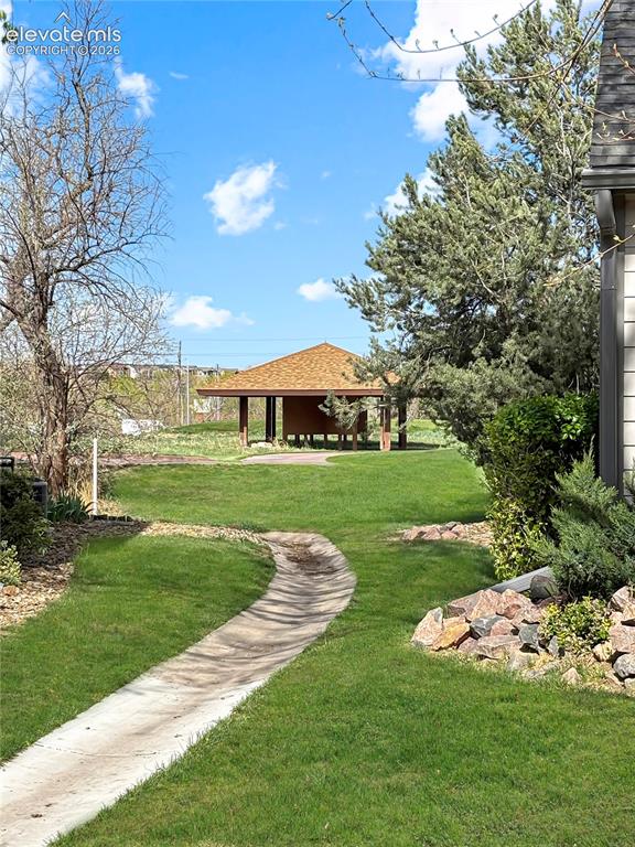 Image 32 of 44: Spacious yard featuring a curved concrete pathway, a free-standing gazebo w