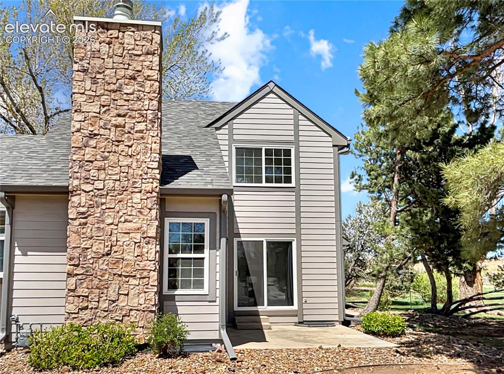 Image 34 of 44: Exterior featuring stone-clad chimney, horizontal siding, and grey shingle