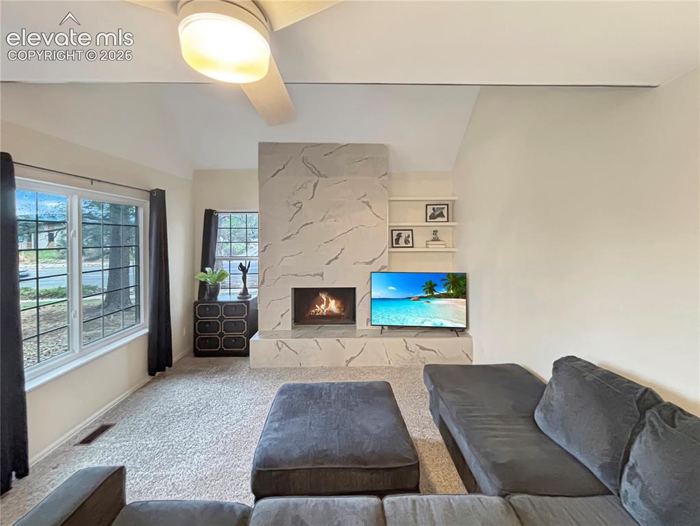 Image 37 of 44: Living area featuring a textured fireplace surround, vaulted ceiling, and r