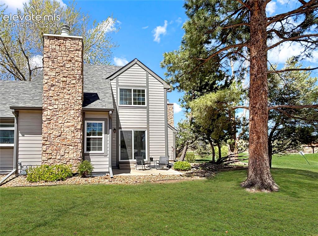 Image 4 of 44: Rear exterior featuring vertical and horizontal siding, a stone-clad chimne