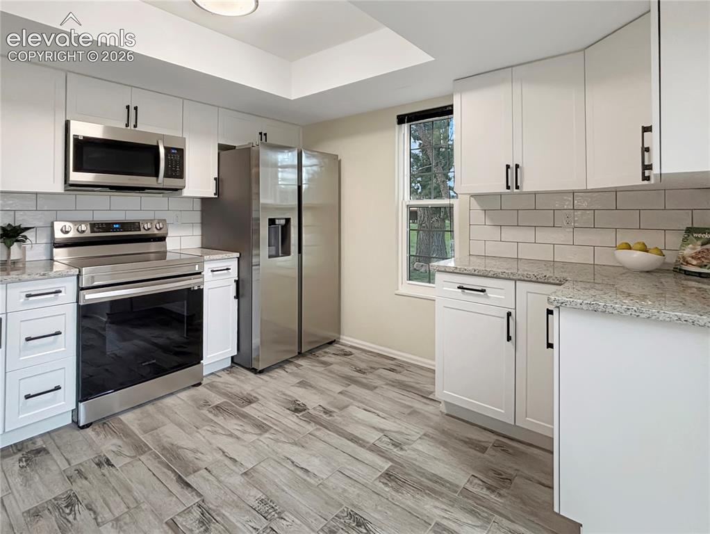Image 5 of 44: Modern kitchen featuring white shaker-style cabinetry with matte black hard