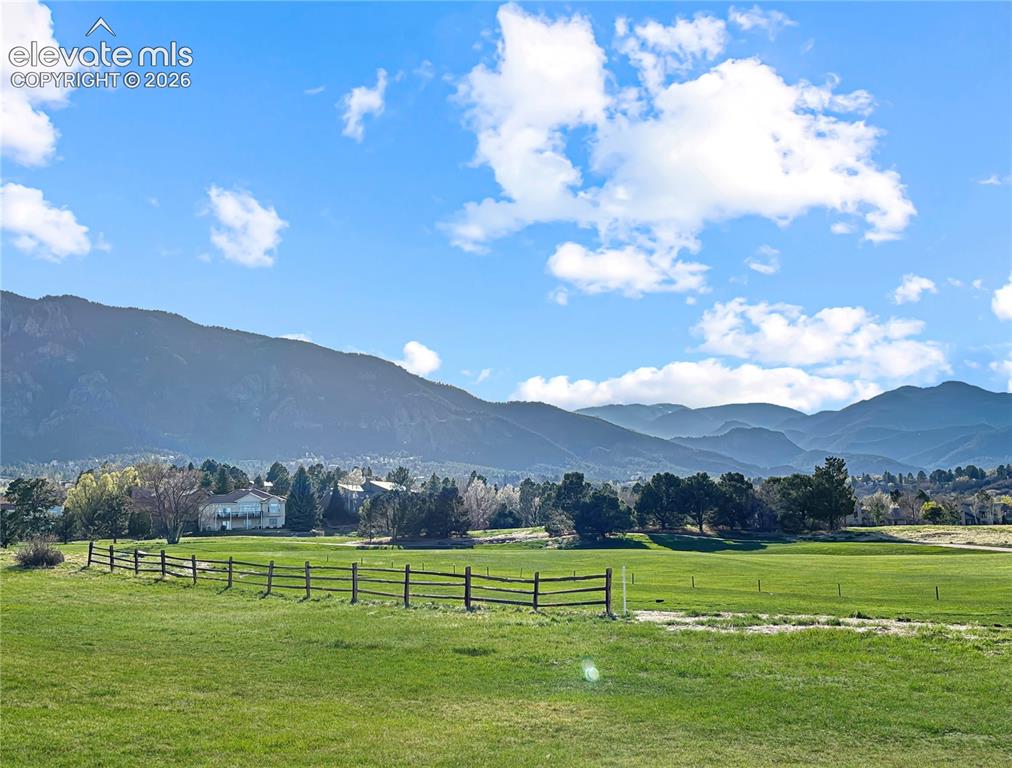 Image 6 of 44: Expansive green landscape featuring a wooden fence line, distant residences