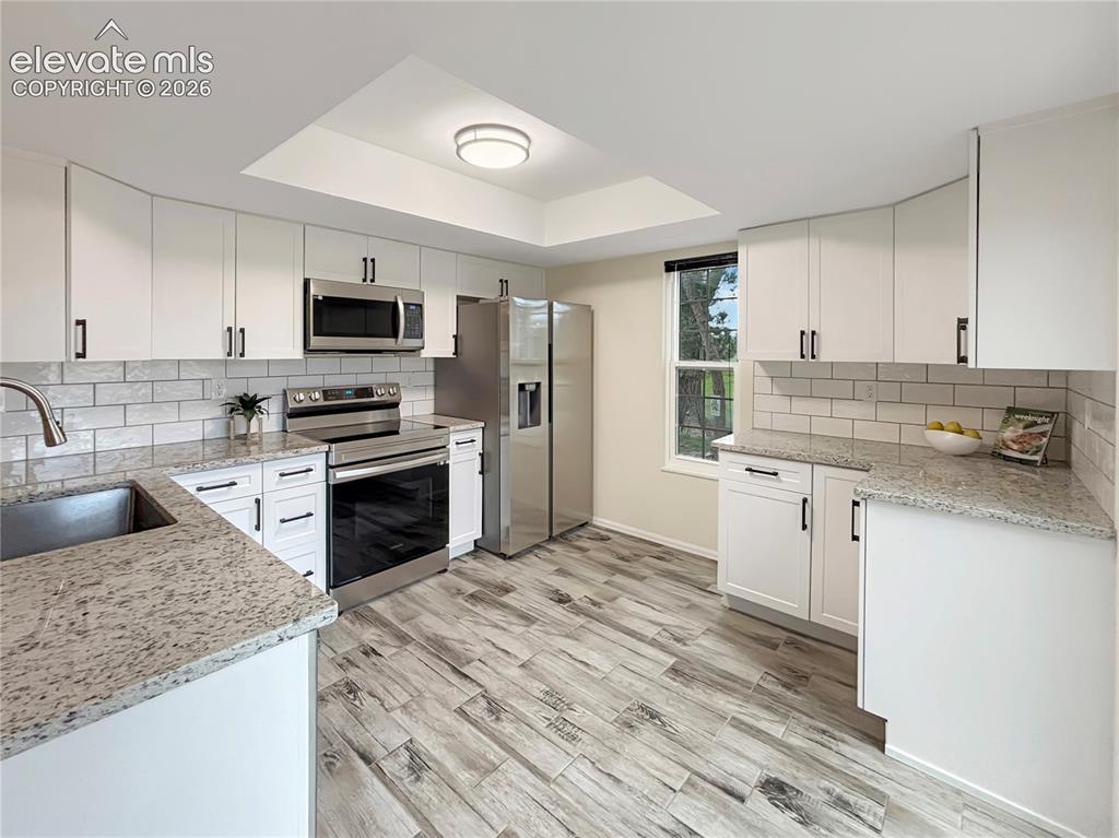 Image 7 of 44: Modern kitchen featuring stainless steel appliances, white cabinetry with m
