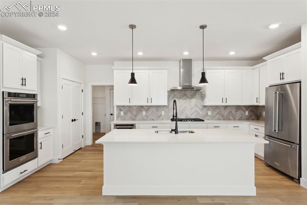 Image 2 of 15: Kitchen featuring appliances with stainless steel finishes, wall chimney ra