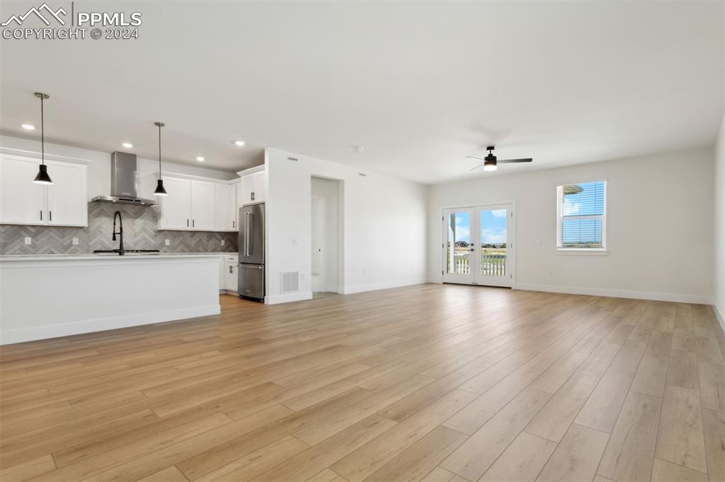 Image 3 of 15: Unfurnished living room with ceiling fan, sink, and light wood-type floorin